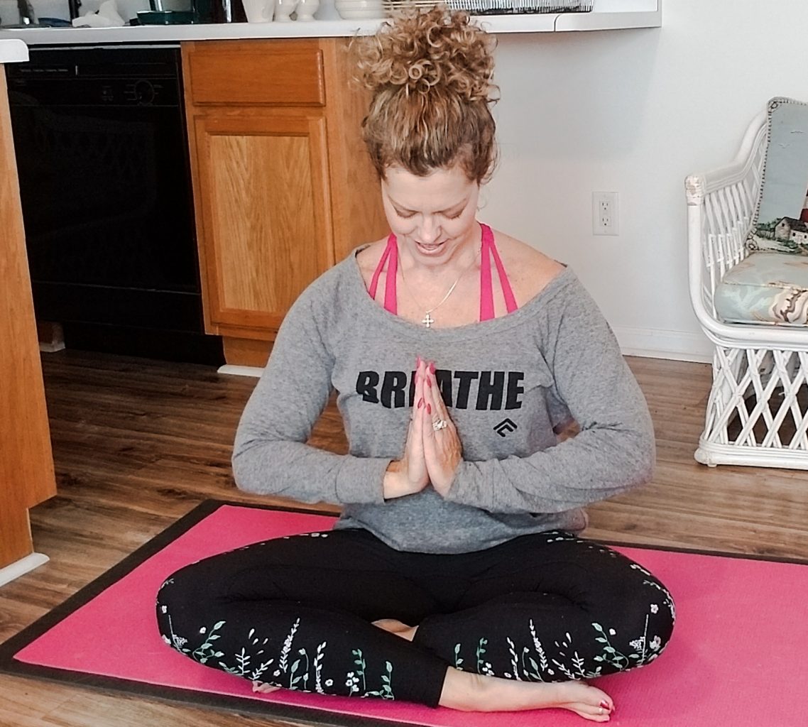 GG sitting on the floor on a yoga mat in cross legged position praying