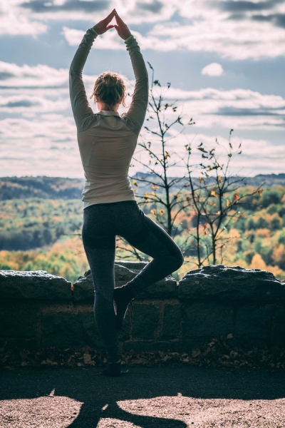 woman starting out to look at mountains and she is in a yoga pose, tree pose