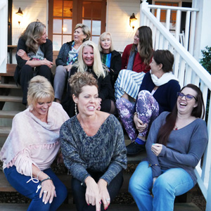 women sitting on stairs at a big southern home and laughing